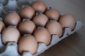 A carton of brown eggs neatly arranged in a paper tray, with soft natural light highlighting the smooth shells, creating a warm and simple kitchen atmosphere.