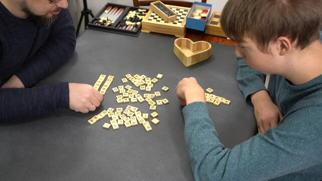Scrabble board game. Players hands on table take letters. Family fun. Father and son spend time together. Different games