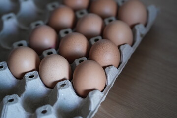 Brown chicken eggs neatly arranged in a paper tray, ready for cooking