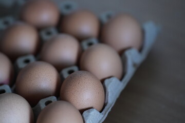 Brown chicken eggs neatly arranged in a paper tray, ready for cooking
