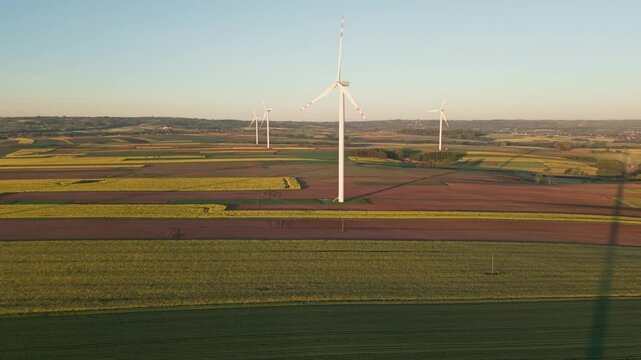 4K, aerial, DJI Air 3S, drone footage at sunrise, showing modern wind turbines producing green energy in the countryside. Ideal for topics related to sustainability, renewable energy.