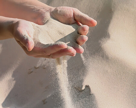 Handful of sand in the women's hands, selective focus. The sand pouring from female hands.	