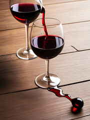 Dropped wine glass and spilled red wine on a wooden table as a symbol of fail, slight unpleasantness