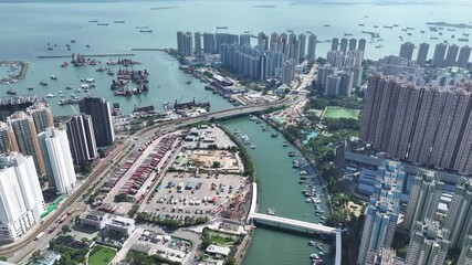 Aerial skyview of Tuen Mun subway extension project in Hong Kong, featuring elevated railway construction along Tuen Mun River and road, new station development and temporary work platforms - Powered by Adobe