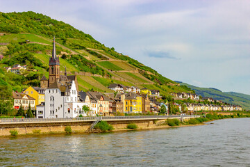 Colorful riverside houses and St. Bonifatius Church in Lorch (Germany) with vineyards on a sunny spring day