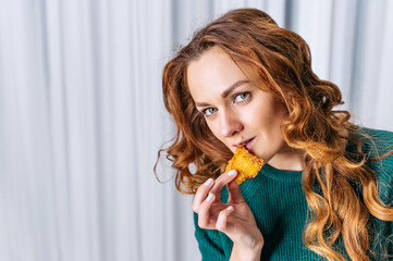 Beautiful woman holding nuggets or breaded shrimp in her hand, concept for delicious takeaway food.