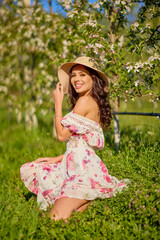 portrait of a beautiful woman in a dress in a blooming apple orchard enjoying a sunny spring day