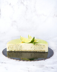 Green Mousse Cake Slice with Lime and Mint. Cross Section Front View on White Marble.