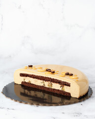 Side view of a layered coffee mousse cake with chocolate sponge and caramelized pear filling. Clean composition on white marble with copy space. Perfect for packaging or editorial use.