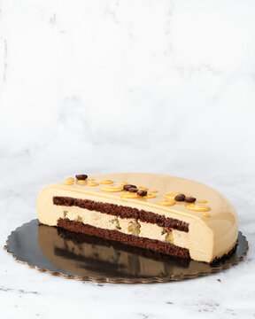 Side view of a layered coffee mousse cake with chocolate sponge and caramelized pear filling. Clean composition on white marble with copy space. Perfect for packaging or editorial use.
