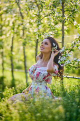 portrait of a beautiful woman in a dress in a blooming apple orchard enjoying a sunny spring day