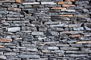 Dry stone wall structure made of stacked natural rocks with rich texture and irregular shapes