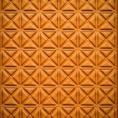 Naklejka premium The warm, natural light highlights the repeating pattern of geometric triangles and squares creating an abstract architectural background in a textured design.