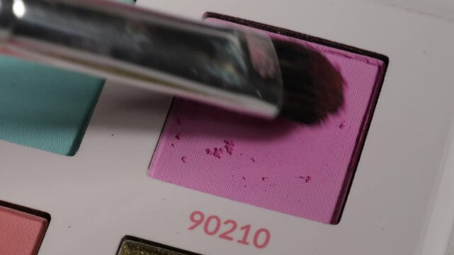 Cloes up shot of very pink eyeshadow and make-up brush.