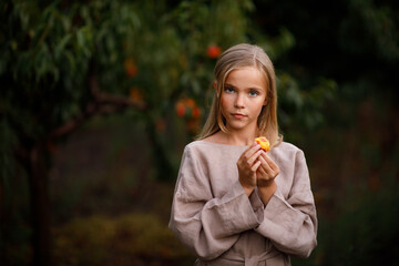 Beautiful happy girl in brown dress in peach garden in summer at sunset