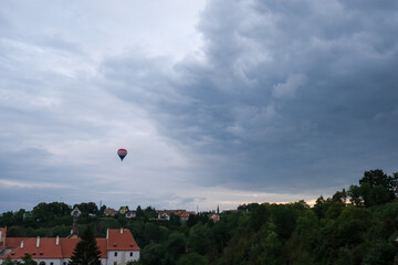 Hot air balloon over village under dramatic sky