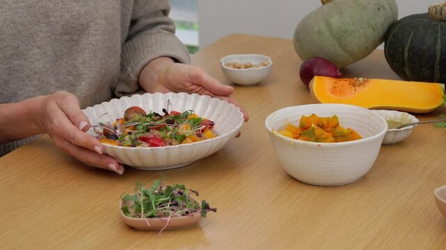Cloes up shot of female hands rotating plate with a salad on the wooden table