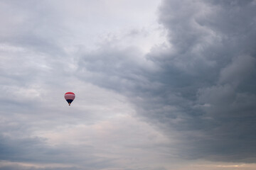 Hot air balloon flying under dramatic cloudy sky