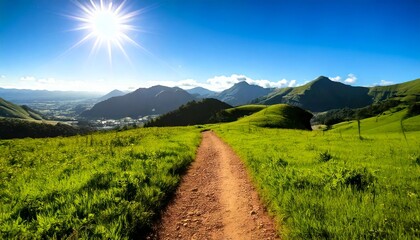 Fototapeta premium Camino de tierra en una exuberante colina verde que conduce a una vista de la montaña bajo un cielo brillante y soleado con espacio para copiar, orientación horizontal