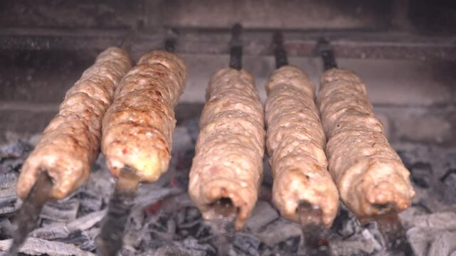 lula kebabs grilling on metal skewers, rotating for uniform browning over high heat, releasing savory aromas