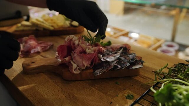 Close-up of slicing and serving meat delicacies on a wooden board. Thin slices of prosciutto, chorizo, lomo, handmade fennel sausage. An exquisite selection of delicious appetizers. Meat plate.