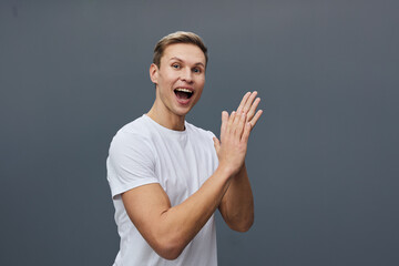 Smiling young man with enthusiastic expression wear casual white t-shirt isolated on plain gray...