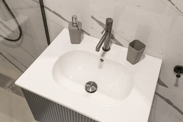 Modern bathroom sink with a minimalist rectangular basin and sleek chrome faucet, complemented by a stylish soap dispenser. 