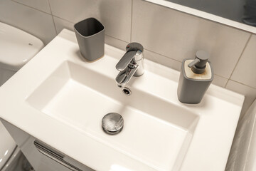 Modern bathroom sink with a minimalist rectangular basin and sleek chrome faucet, complemented by a stylish soap dispenser. 