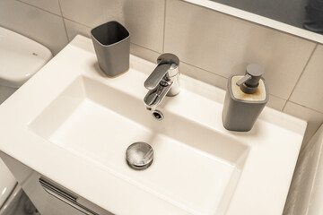 Modern bathroom sink with a minimalist rectangular basin and sleek chrome faucet, complemented by a stylish soap dispenser. 