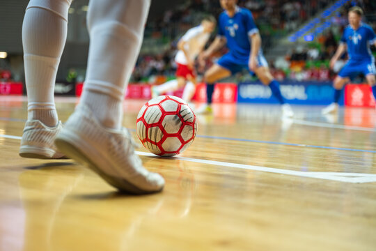 Detail of futsal ball and players legs.