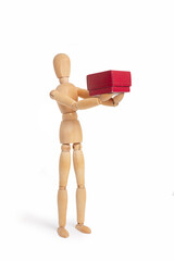 A wooden mannequin toy holding with both hands a red box on white background with copy space