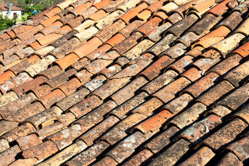 Old worn tiles. Building material background. Red tiles that require maintenance. Roofing, waterproofing. Surface. Top view, above.