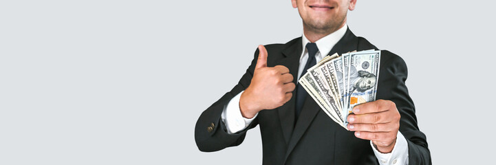 Banner, Cheerful businessman in a suit holds american dollars in his hands and raises his thumb up...
