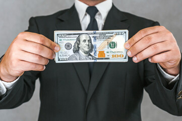 Close-up, American dollars money in the hands of a business man. White and gray background.