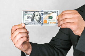 Close-up, American dollars money in the hands of a business man. White and gray background.