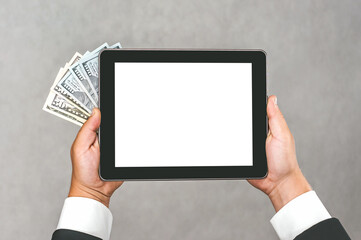 A man in a business suit holds a mock-up of a tablet with money on a gray-white background.