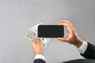 Smartphone with American dollars in the hands of a businessman. on a light gray background.