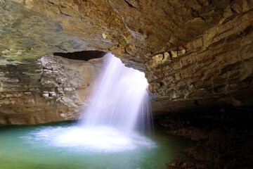 Saltinsky waterfall. A stream of water flowing inside the cave.