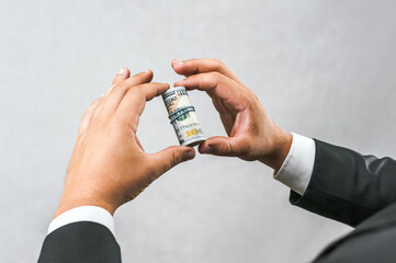 Close-up of a bundle of American money in the hands of a businessman. On a light gray background.