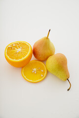 Fotografia de frutas frescas com composição minimalista em fundo branco. Duas peras e uma laranja...