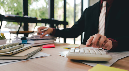 Accountant working at desk using calculator to calculate company's annual financial and tax report....