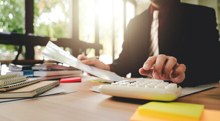 Accountant working at desk using calculator to calculate company's annual financial and tax report....