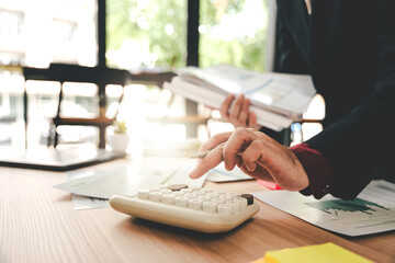 Accountant working at desk using calculator to calculate company's annual financial and tax report....