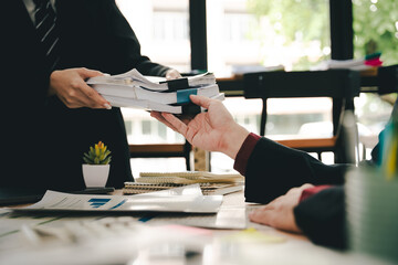 Employees working with a lot of documents, searching for documents, accounting for income and expenses, recording taxes, and working hard.