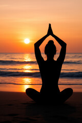 Silhouette of woman in lotus position at beach during golden sunset