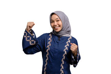 Excited young Asian Muslim woman raising fists, celebrating victory with euphoric facial expression...