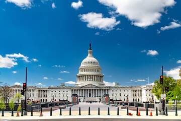 Panoramic view of Capitol building in Washington D.C. under white clouds. Tourists walking on the...