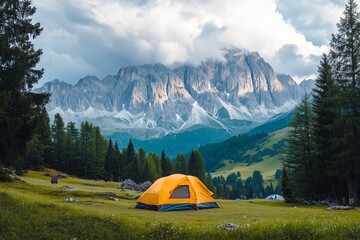 Yellow tent set up in scenic alpine meadow with majestic mountain view.