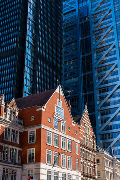 Modern skyscrapers surrounding a traditional red-brick building, highlighting architectural contrast and the evolution of dense financial urban zones.