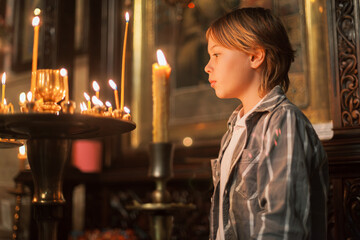 Young boy praying and lighting candles in an Orthodox church in Georgia. Moments of reverence, faith, and spiritual reflection